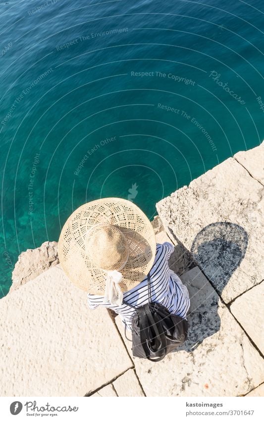 Grafische Darstellung der Draufsicht einer Frau mit großem Sommersonnenhut, die sich am Pier am klaren türkisfarbenen Meer entspannt. Wasser Sonne Hut Freizeit