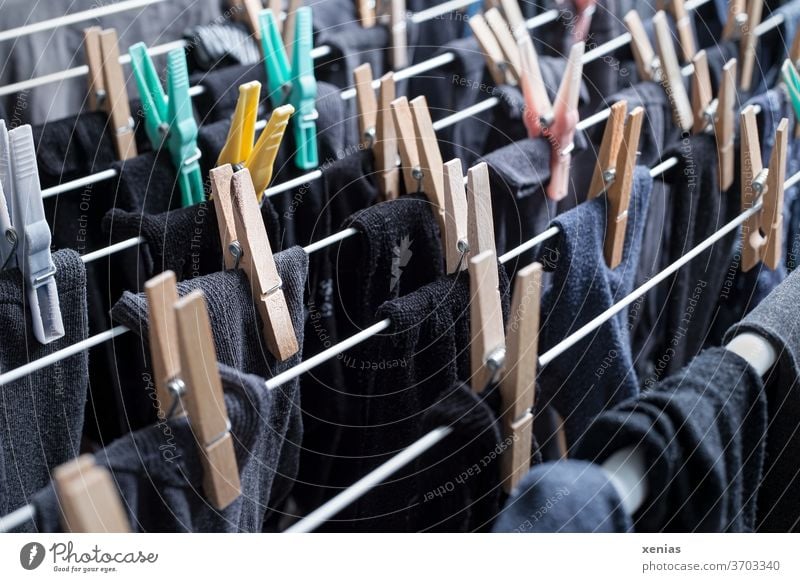 Dunkle Sockenwäsche - schwarze, graue und blaue Strümpfe hängen mit Wäscheklammern zum Trocknen auf dem Wäscheständer Klammer Haushalt Waschtag trocknen