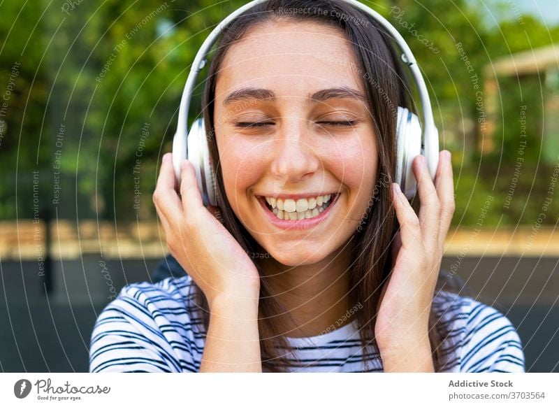 Ruhige Frau beim Musikhören in der Stadt zuhören Kopfhörer genießen Gesang sorgenfrei verträumt zufrieden Großstadt Glaswand Gebäude Spiegel