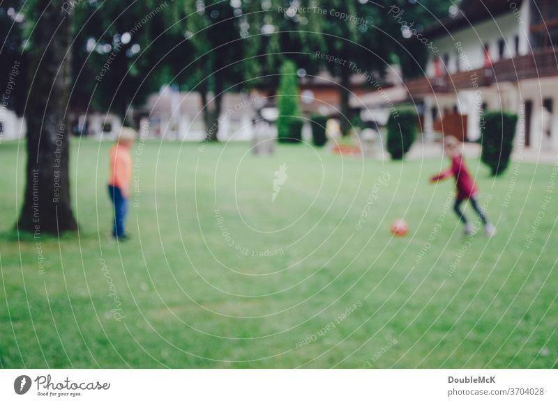 Zwei Kinder spielen Fußball auf Wiese, Foto ist unscharf Sport Ball Spielen Gras grün Rasen Ballsport Freizeit & Hobby Außenaufnahme Farbfoto Tag sportlich