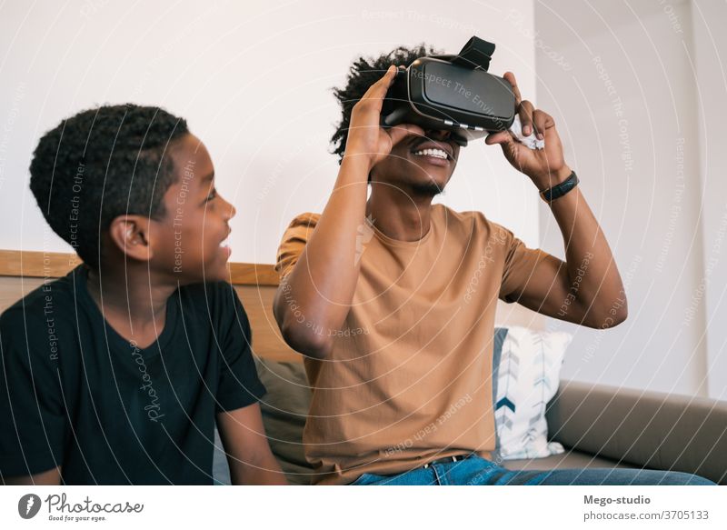 Vater und Sohn spielen mit VR-Brillen. Spiel Video Zusammensein Afroamerikaner entspannend bezaubernd elektronisch Partnerschaft Videospiel