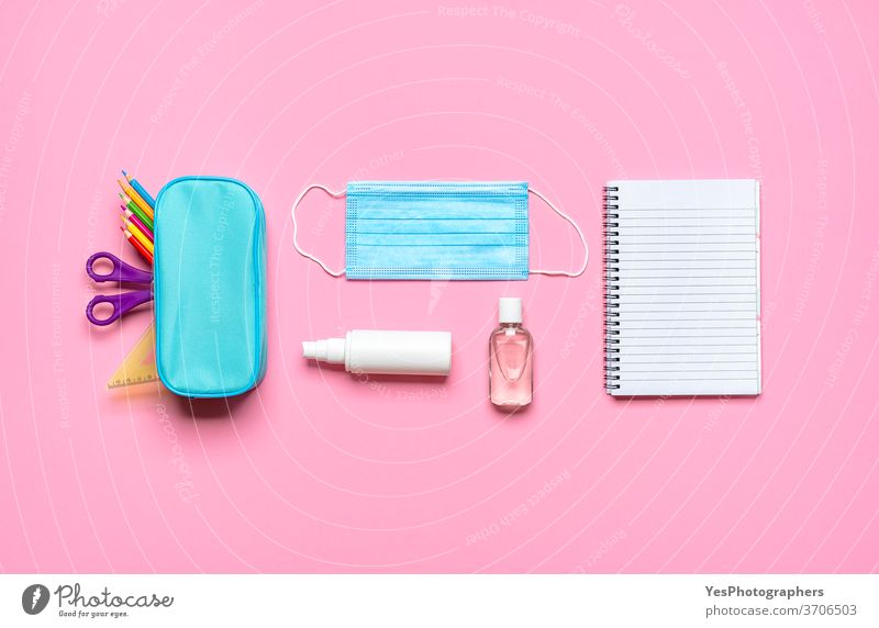 Schulsachen auf einem rosa Schreibtisch. Zurück zu Pandemie-Anforderungen für die Schule Rücken zurück zur Schule Hintergrund blanko blau Konzept Korona COVID