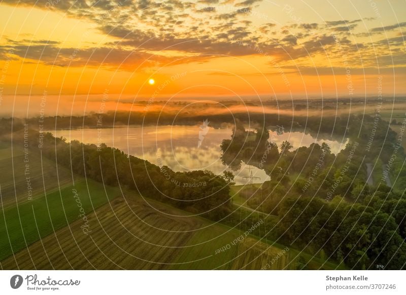 Deutschland, ein kraftvoller Sonnenaufgang über einem nebligen See, Moment purer Natur. Morgen Feld Himmel Hintergrund Sommer glühen Nebel Baum Wasser orange