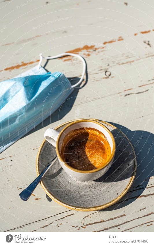 Espresso trinken im Café mit Mundschutz weil Corona ist Gastronomie Kaffee Tasse Maske Kaffeepause genießen Maskenpflicht Heißgetränk Tisch Sonne Kaffeetrinken