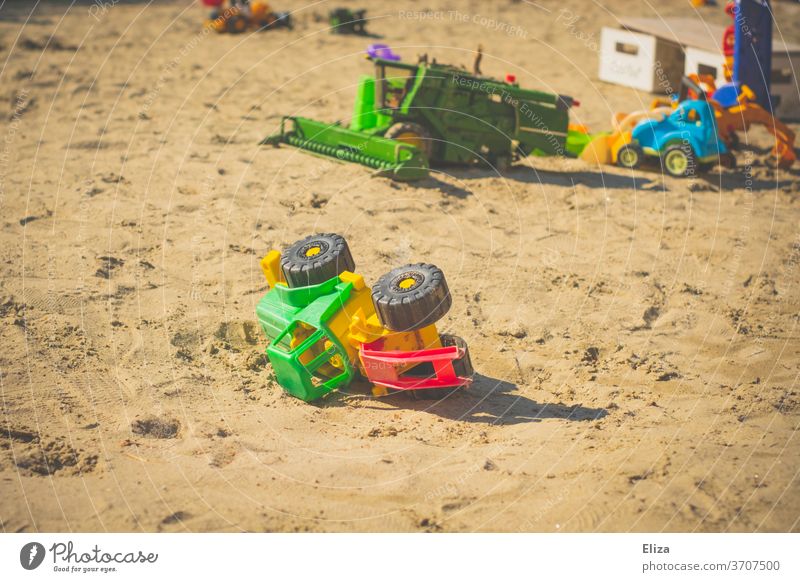 Spielzeug Traktor im Sandkasten. Draußen spielen mit Sandspielzeug. Spielzeugtraktor Spielen Kindheit Kindergarten Spielplatz Sommer Kinderspiel draußen bunt