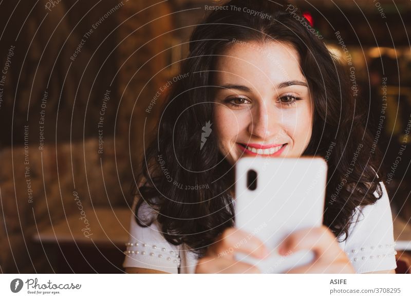 Glückliche junge schöne Frau benutzt ihr Smartphone in einer Bar Mädchen Café Porträt Lächeln Person Freude Menschen zahnfarben Gesicht abschließen Handy
