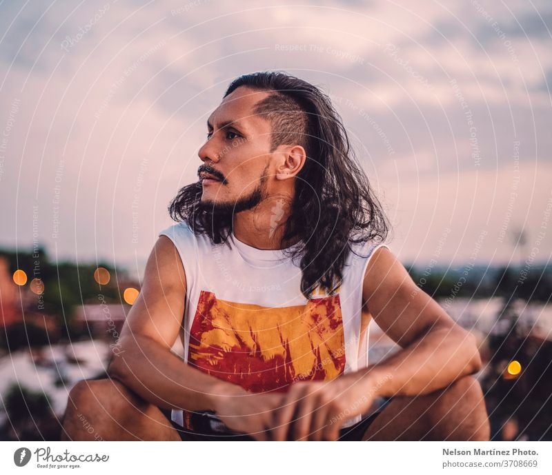 Bildnis eines hispanischen Mannes mit langen Haaren. Wir sehen die Stadt mit einem Bokeh-Hintergrund. vereinzelt Person weiß Erwachsener stolz Vorderseite
