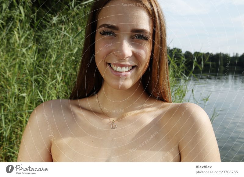 Nahes Portrait einer jungen Frau mit in einem See vor Schilf Licht sportlich feminin Gefühle emotional Blick in die Kamera Porträt Zentralperspektive