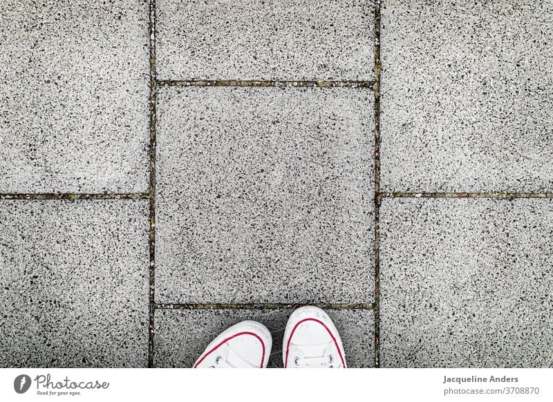 Auf dem Gehweg spazieren Straße gehwegplatten Fußweg Schuhe füße Blick nach unten Asphalt stehen Frau Außenaufnahme grau weiß Tag Mensch Form Muster urban