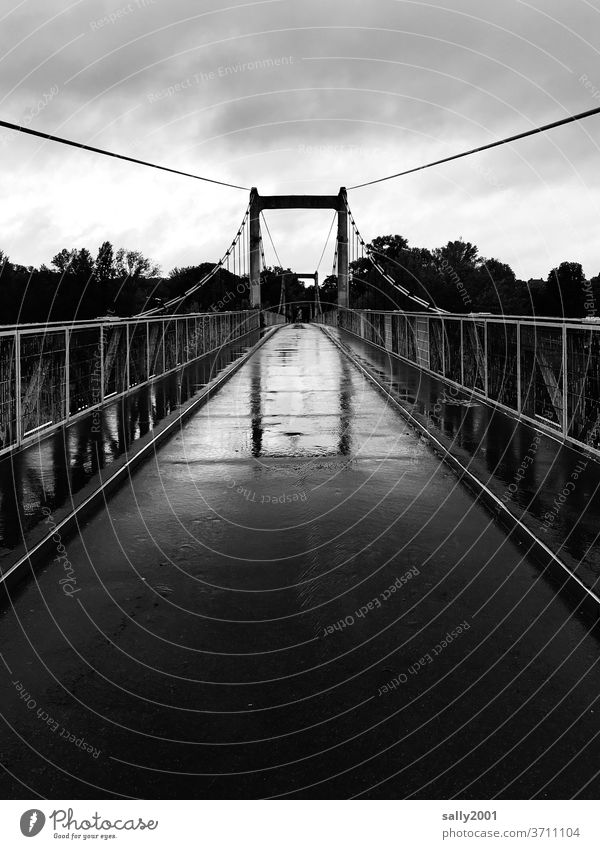 Brücke im Regen... schmal Fußgängerbrücke Geländer Hängebrücke Asphalt schlechtes Wetter nass Schwarzweißfoto Spiegelung Reflexion & Spiegelung Wege & Pfade