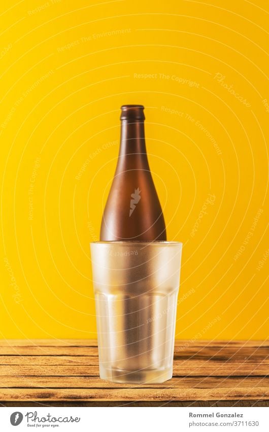 Leeres Bierglas, Flaschenbier auf Holzuntergrund und gelber, selektiver Fokus. Bierflaschen Club Oktoberfest Glas bayerisch Stadtfest München Schuss Bayern