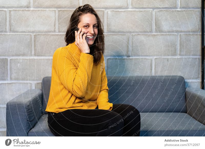 Fröhliche junge Frau spricht auf Smartphone reden Glück lässig heiter Mobile Kommunizieren zufrieden Telefon Nachrichten modern Loft Lachen Gerät Apparatur
