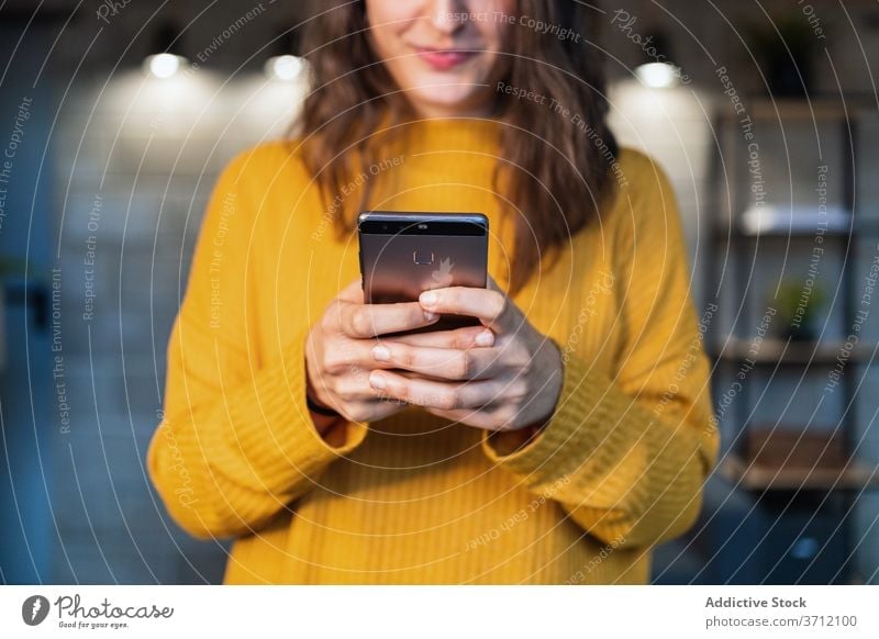 Anonyme Frau auf Smartphone jung lässig Mobile Kommunizieren zufrieden Telefon Glück modern Loft benutzend Gerät Apparatur Nachricht Anschluss Browsen Text