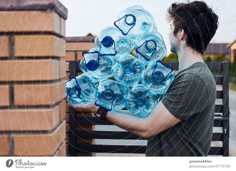 Junger Mann wirft leere gebrauchte Plastikwasserflaschen in den Mülleimer. Sammelt Plastikabfälle zur Wiederverwertung ein. Konzept der Kunststoffverschmutzung und zu vieler Kunststoffabfälle. Umweltproblematik