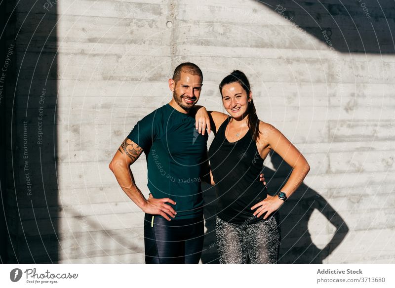 Sportliches Paar, das sich beim Training auf der Straße umarmt Umarmung sportlich Athlet Großstadt Partnerschaft Liebe Sportbekleidung Lächeln Fitness Glück