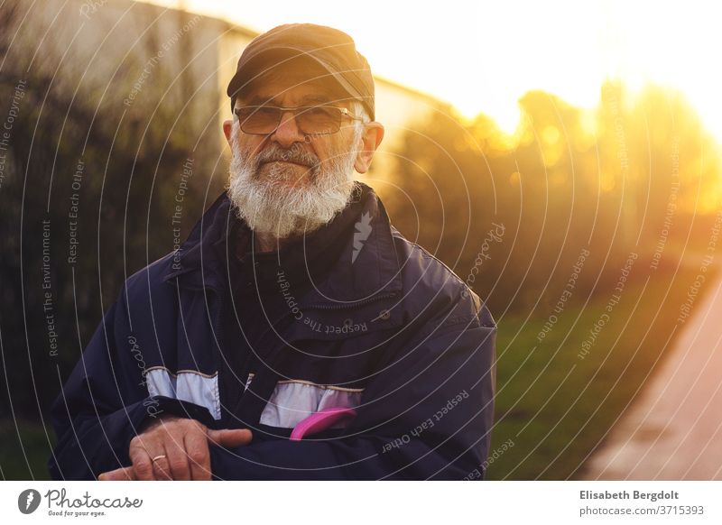 Portrait eines 75 Jahre alten Mannes mit Brille und Bart, draußen, bei Sonnenuntergang älterer mann Porträt Senior Spaziergang Männlicher Senior 60 und älter