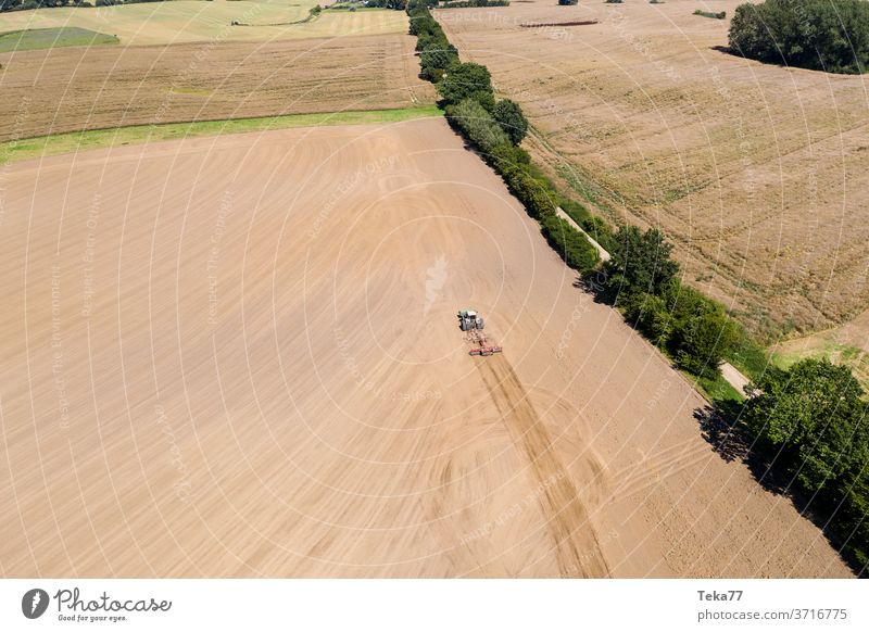 ein Traktor in einer Agrarlandschaft mit einem Pflug von oben Traktor von oben Traktor mit einem Pflug Feld Wiese Landwirtschaft Bauernhof trocknen Natur Erde