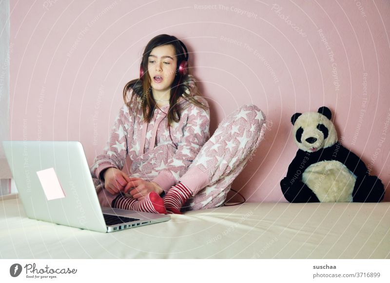 jugendliche sitzt vor ihrem laptop und hört musik oder chattet mit freunden. das pandabär-stofftier ist auch dabei .. Jugend Jugendliche Teenager Kind Mädchen
