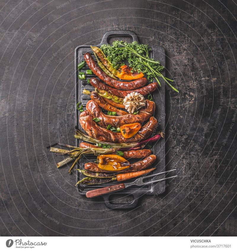 Grillwürste auf Gusseisenplatte. Ansicht von oben Bratpfanne gegrillt Lebensmittel gießen bügeln Teller Wurstwaren Paprika Frühlingszwiebel Knoblauch