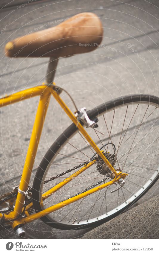 Hinterteil eines gelben vintage Rennrades Fahrrad Fahrradfahren retro Sattel Ledersattel Sport Lifestyle trendy Mobilität hip Straße Hinterreifen