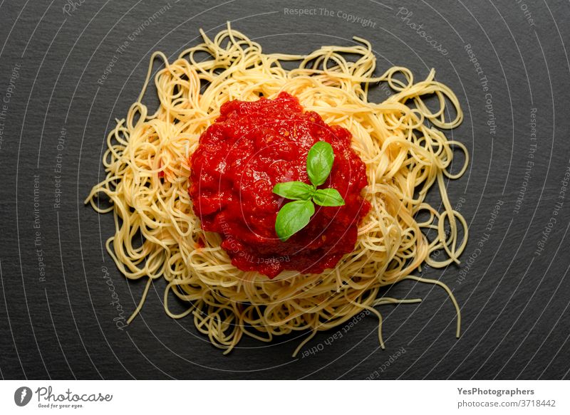 Spaghetti mit Tomatensauce auf einem schwarzen Granitteller. Gekochte Spaghetti mit roter Sauce. obere Ansicht Hintergrund gebacken Basilikum Kohlenhydrat