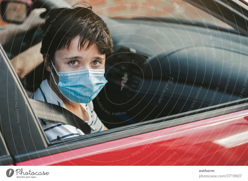 Kind mit medizinischer Maske, das in einem Auto fährt Coronavirus Virus medizinische Maske PKW KFZ Sicherheitsgurte Seuche Pandemie Quarantäne Familie covid-19