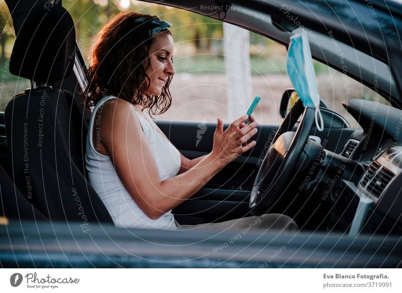 junge Frau in einem Auto. Schutzmaske, die am Rückspiegel hängt. Reisen und neues Normalkonzept PKW fahren Corona-Virus reisen Pollen Krankheit Prävention