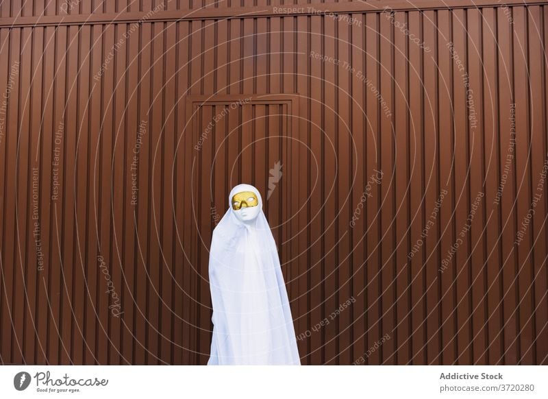 Anonymes Kind im Geisterkostüm auf der Straße Tracht Halloween Mundschutz Maskerade Feiertag Veranstaltung Herbst Großstadt Gebäude urban Anzug beängstigend