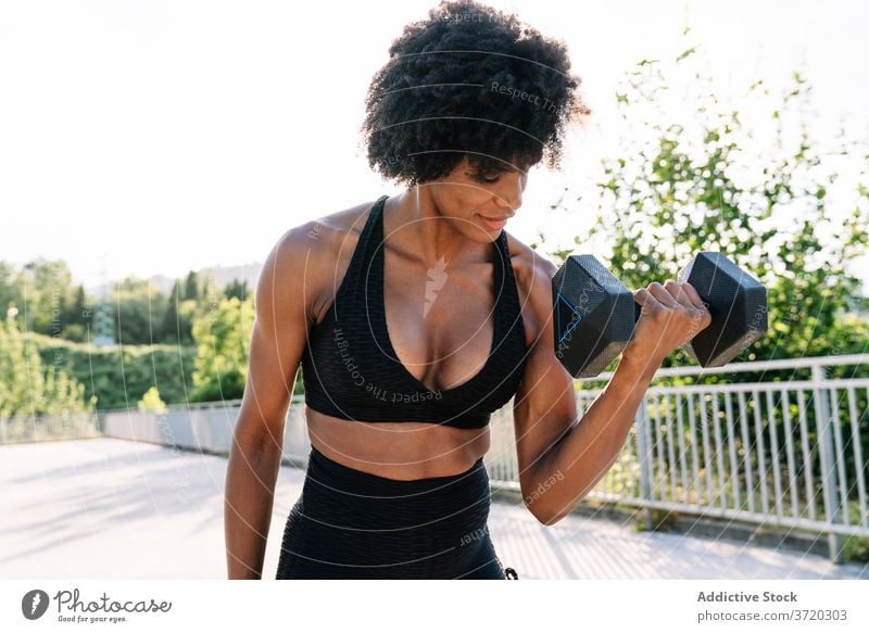 Starke Sportlerin beim Training mit Kurzhantel Übung Frau Pumpe Muskel manifestieren Bizeps stark muskulös Körper Form Energie passen Wellness schlank Sommer