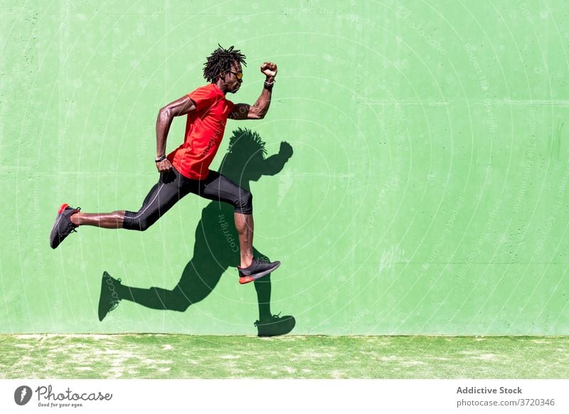 Fitter männlicher Sportler beim Training auf dem Sportplatz springen Mann Sommer intensiv passen Moment Übung ethnisch schwarz Afroamerikaner Sportkleidung