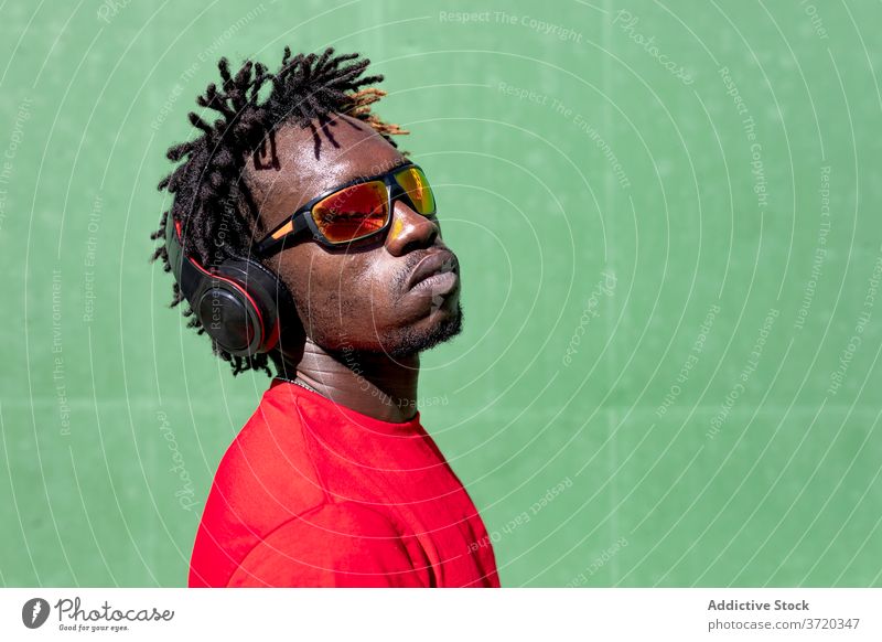 Schwarzer Sportler beim Musikhören zuhören Kopfhörer Mann Rastalocken Athlet vorbereiten Training genießen männlich ethnisch schwarz Afroamerikaner Gesundheit
