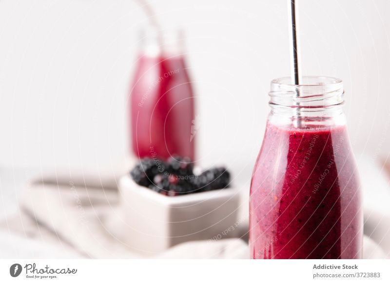 Cropshot einer Glasflasche mit rosa hausgemachtem Beeren-Smoothie, mit einem Metallstrohhalm. Flasche Farbe Ausschnittaufnahme trinken Essen und Trinken Früchte
