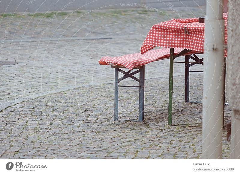 Rotweiß kariert, Bierbank und Tisch an einer Straßenecke mit Kopfsteinpflaster rot Muster Farbfoto Menschenleer Tag Außenaufnahme Tischwäsche Stoff gemütlich