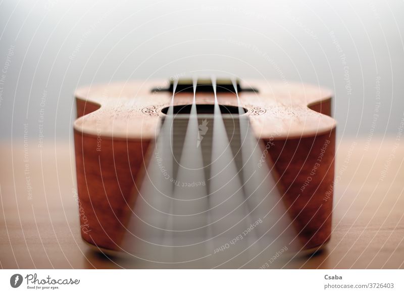 Braune Ukulele auf Holzgrund mit geringer Feldtiefe Instrument akustisch Musik braun hölzern Hintergrund Gitarre Musical Schnur Rosette hawaiianisch Objekt