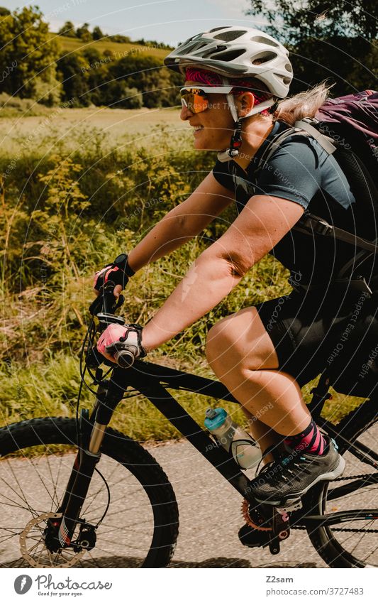 Junge Frau auf dem Mountainbike bei einer Radtour mountainbike radtour junge frau mädchen helm sportlich outdoor sonnebrille trikot rucksack lächeln spaß