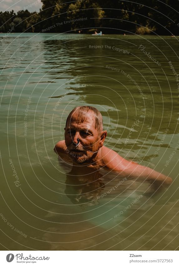 Rentner beim Schwimmen im See schwimmen freizeit rentner rente sommer see gewässer wasser sport bewegung nasenklammer sportlich braun alter mann portrait