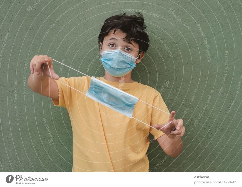 Kind mit medizinischer Maske, das eine medizinische Schutzmaske hält Coronavirus Virus medizinische Maske Seuche Pandemie Quarantäne covid-19 Symptom Medizin