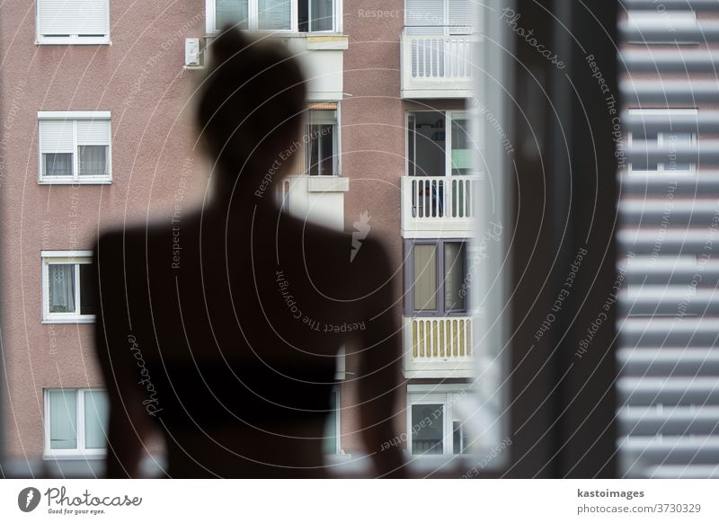 Hausquarantäne und soziale Distanzierung während einer Covid-Pandemie. Silhouette einer einsamen, weißen Frau, die am Fenster steht und ängstlich nach draußen schaut. Coronavirus-Infektion, Pandemien, Krankheitsausbrüche
