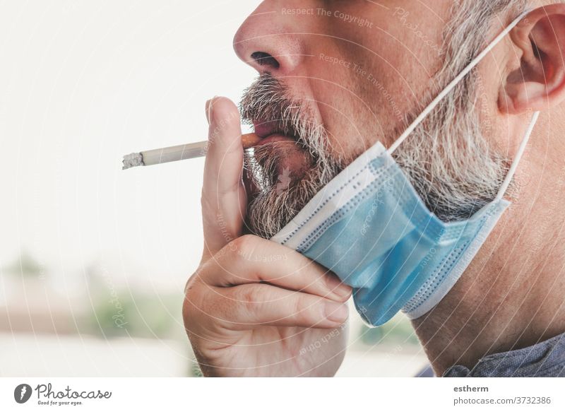 covid-19,Mann mit medizinischer Maske, der auf der Strasse eine Zigarette raucht Coronavirus 2019-ncov ungesund Rauch Virus Seuche medizinische Maske Verbot