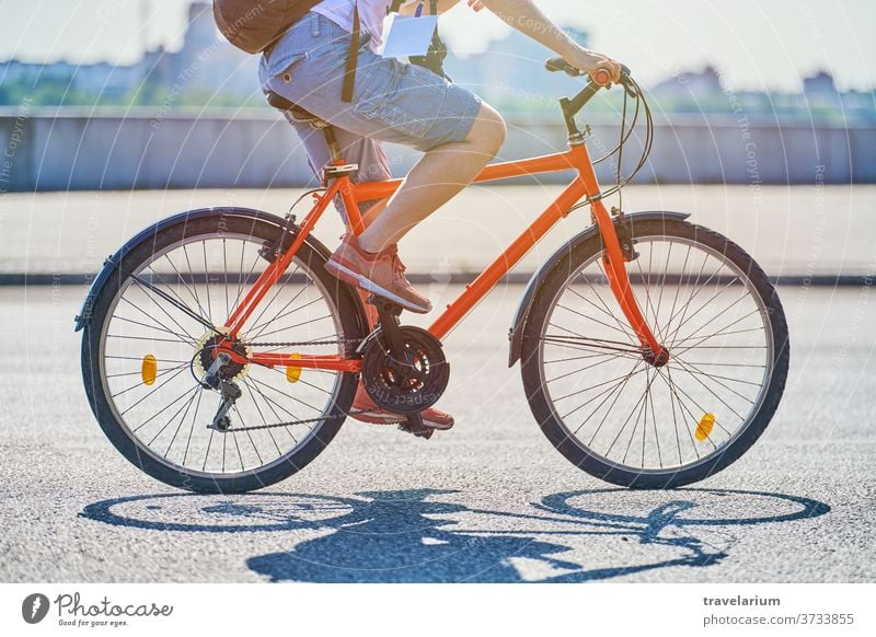 Junge Frau fährt auf einem Fahrrad auf der Stadtstraße Mädchen Großstadt Mitfahrgelegenheit Straße Radfahrer Reporter Plakette Fotokamera Rucksack Sonnenlicht