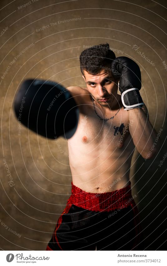 Junger Mann, der in der Studioaufnahme posiert. Thai Boxer Schweiß kämpfen Kick Unterarme Gewalt Kraft stark männlich wettbewerbsfähig kardiovaskulär Kämpfer