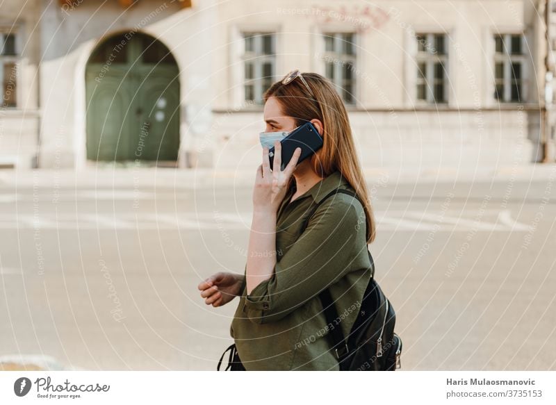 Frau mit Gesichtsmaske telefoniert draußen, Profilansicht 2020 Erwachsener schön blau Kaffee Kaukasier Kind Kindheit Großstadt Konzept Coronavirus covid-19