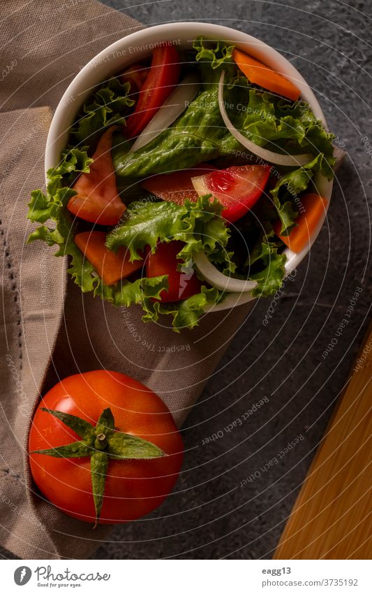Tomaten im Salat in einer weißen Schale auf grauem Hintergrund Salatbeilage Lebensmittel Lebensmittelgeschäft Stilleben Gemüse organisch mediterran Hintergründe