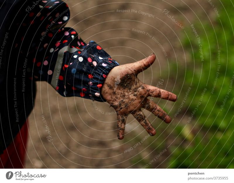 Eine matschige, dreckige Kinderhand. Kind spiel bei Regen in Regenbekleidung im Matsch kinderhand kindheit kinderspiel spaß regen regenkleidung regenjacke