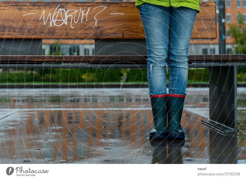 Sitzband mit Schriftzug "warum?" im Regen mit Kinderbeinen in Gummistiefel Farbfoto Außenaufnahme authentisch Freiheit Tag Straße Kleinstadt Symbole & Metaphern