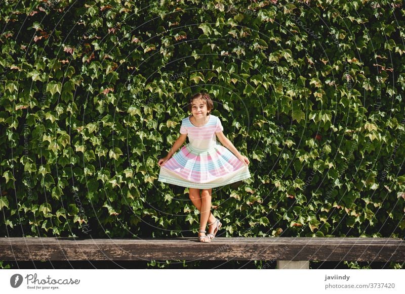 Glückliches 9-jähriges Mädchen in einem hübschen Kleid spielt Kind wenig Blätter Wand urban Sommer niedlich Großstadt Frau jung Stil Kindheit Mode Straße schön