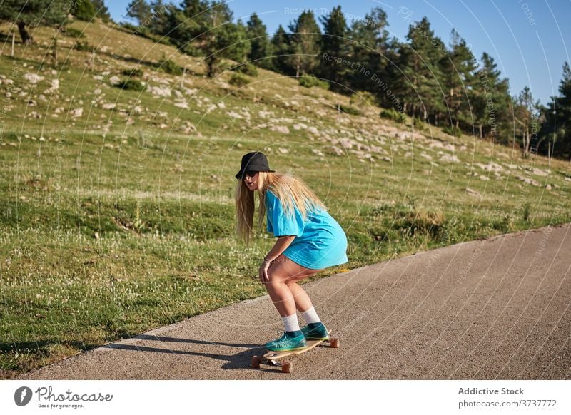 Frau fährt Skateboard entlang der Straße in den Bergen Skater Mitfahrgelegenheit Hipster Berge u. Gebirge Sommer jung Schlittschuh Wochenende ländlich Sport