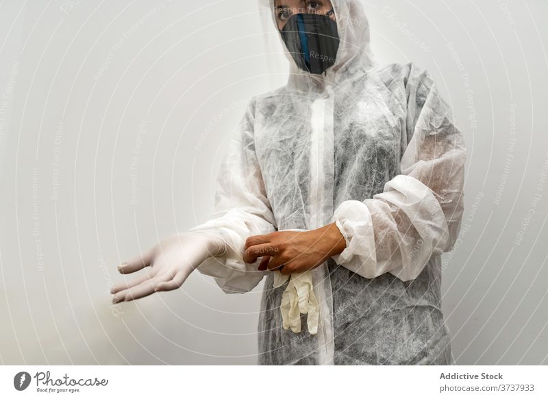 Arzt im PSA-Anzug zieht Handschuhe an Sanitäter Coronavirus behüten Mundschutz angezogen COVID ansteckend Sicherheit ppe Frau Medizin medizinisch professionell
