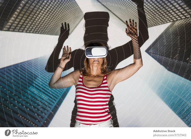 Aufgeregte Frau in VR-Headset erkundet virtuelle Stadt Virtuelle Realität Wolkenkratzer Gebäude Großstadt urban Schutzbrille berühren aufgeregt Erfahrung