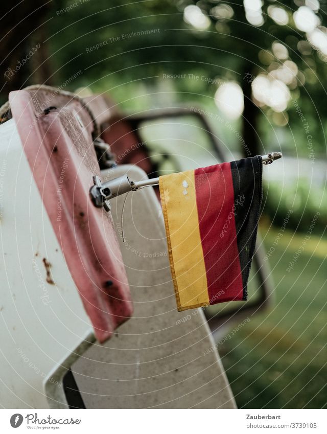 Kleines Motorboot an Land, lehnt an einem Baum, mit Deutschlandfahne gestrandet alt Verfall kippen gekippt Kunststoff Rumpf angelehnt vergeblich Abstieg hilflos